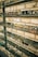 Multiple pairs of eyeglasses are neatly displayed on glass shelves against a brick wall. The glasses vary in style, shape, and color, creating a visually appealing array.