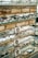 A display of various eyeglasses is arranged neatly on shelves set against a brick wall. The shelves are made of glass, reflecting light and displaying multiple styles and colors of frames. There are informational cards placed among the glasses featuring the word 'EYES' alongside a simple graphic of eyeglasses.