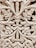 Intricate wooden carving featuring elaborate floral and leaf patterns, with a symmetrical design. The craftsmanship showcases detailed scrollwork and a textured surface.