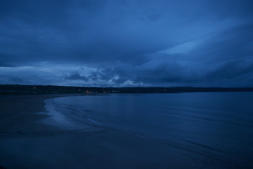 a view of a beach at night with dark clouds