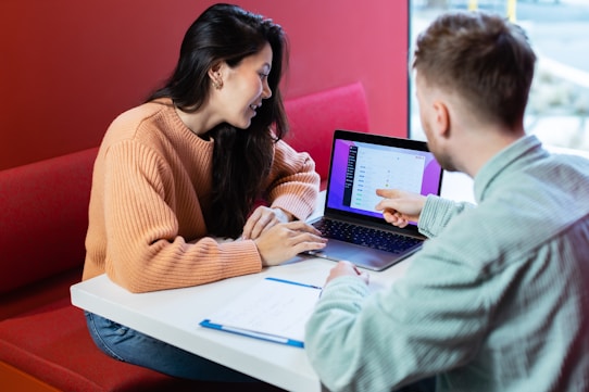 a man and a woman sitting at a table with a laptop