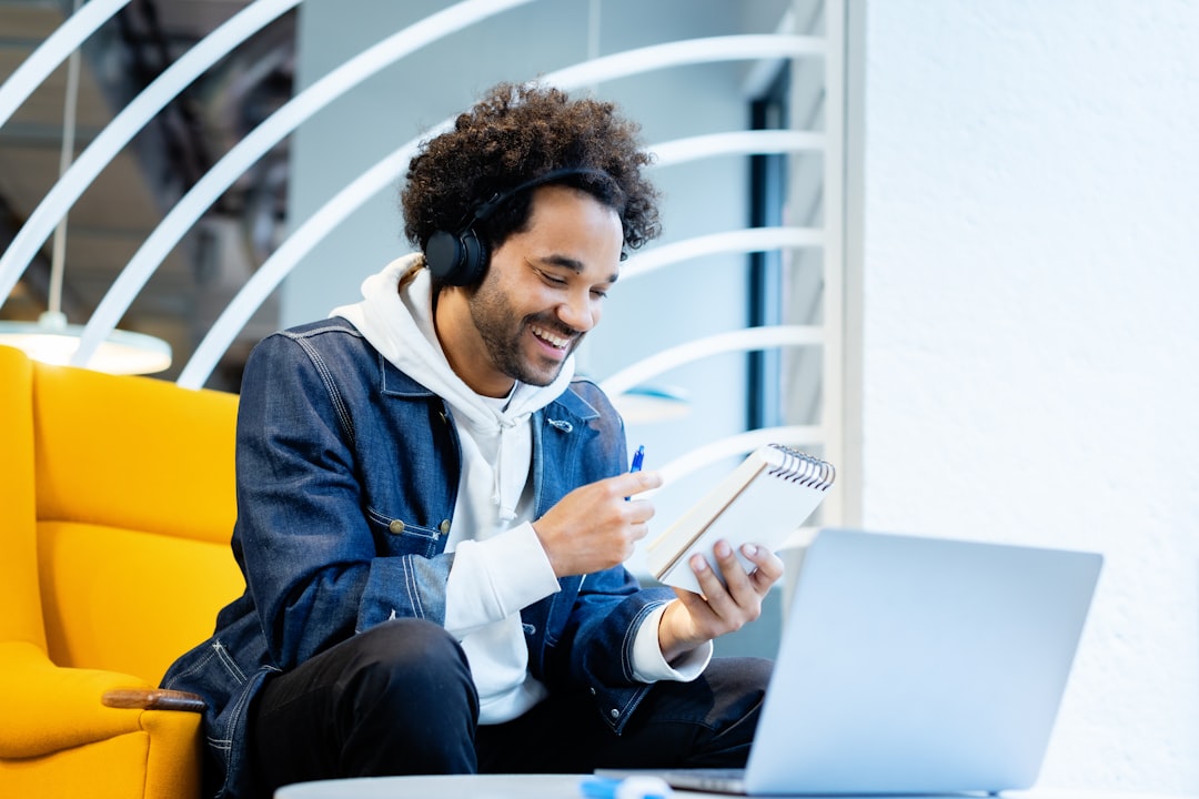 a man sitting in front of a laptop computer, A freelancer taking notes while working in a coworking space