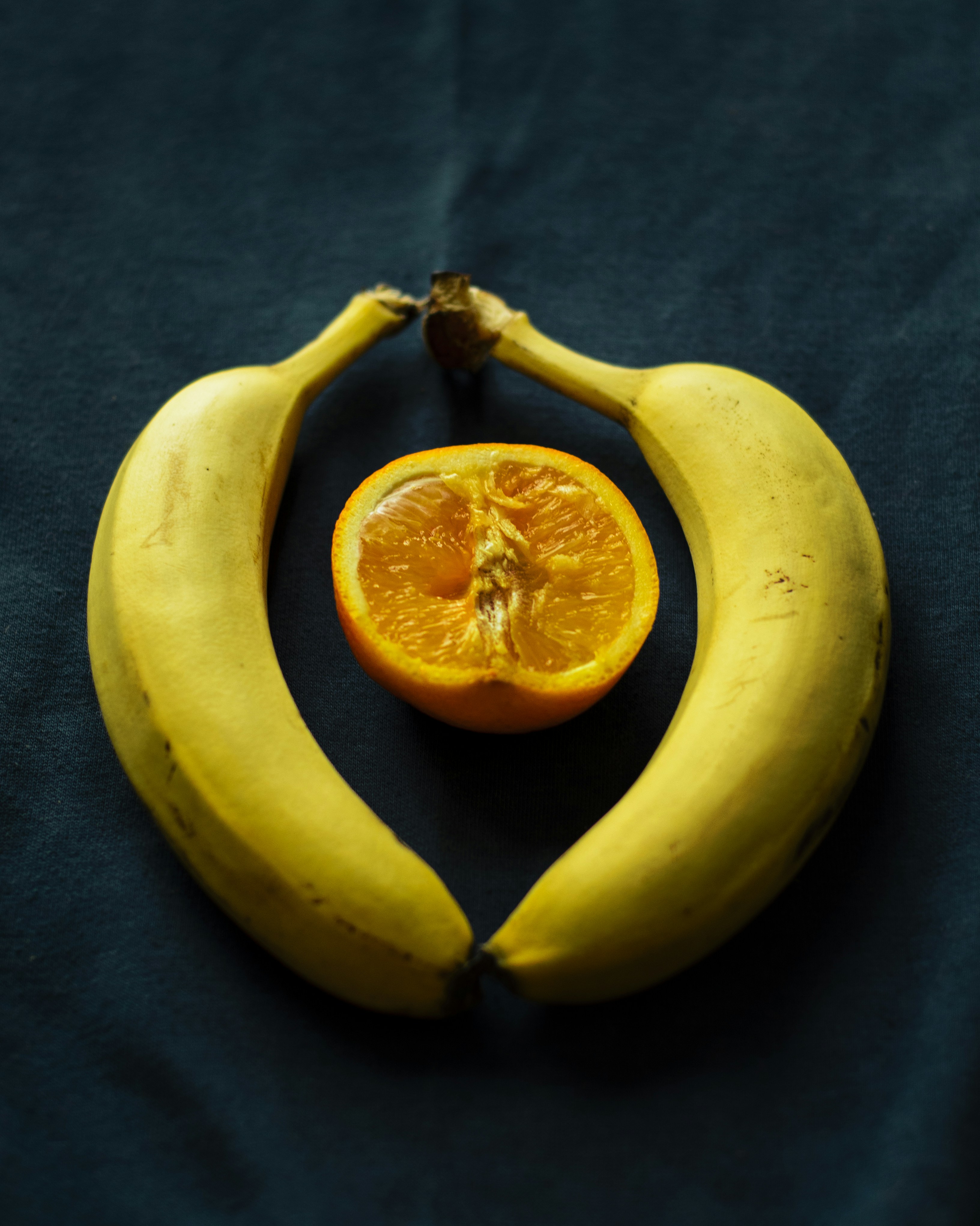 an orange cut in half sitting on top of a banana