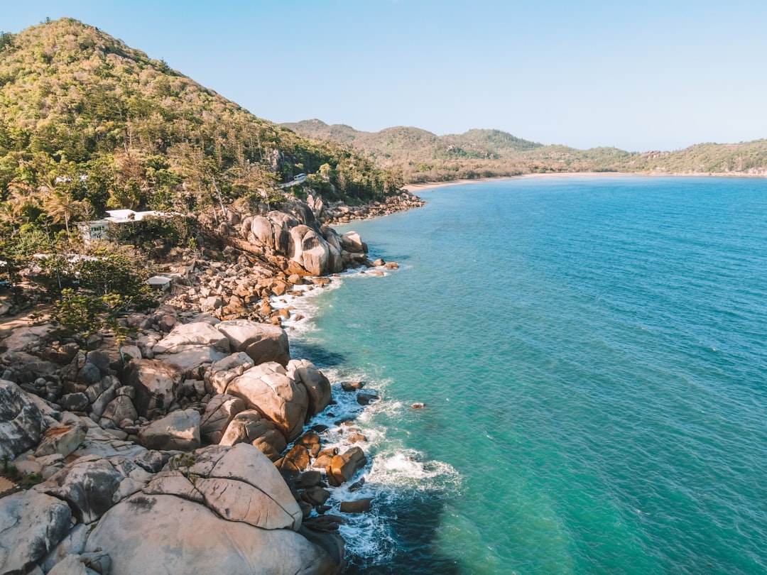 an aerial view of a rocky beach with clear blue water,