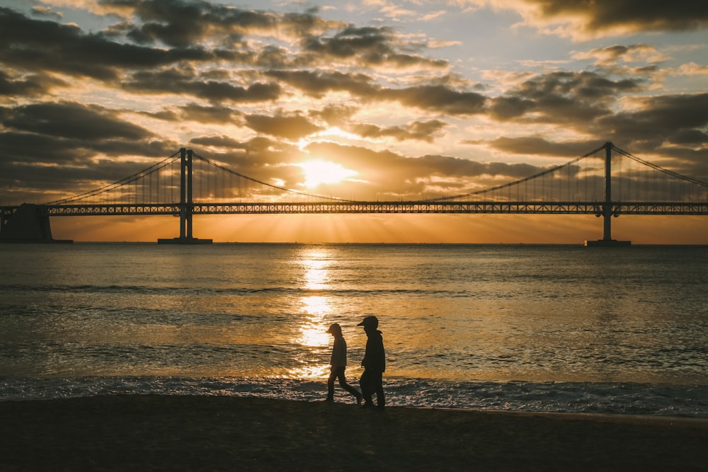 a couple of people standing on top of a beach