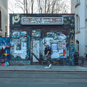 A candid street shot of a man in terravibe’s earth brown pants walking past urban graffiti