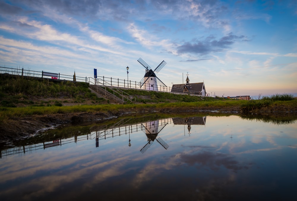 a windmill sitting on top of a hill next to a body of water