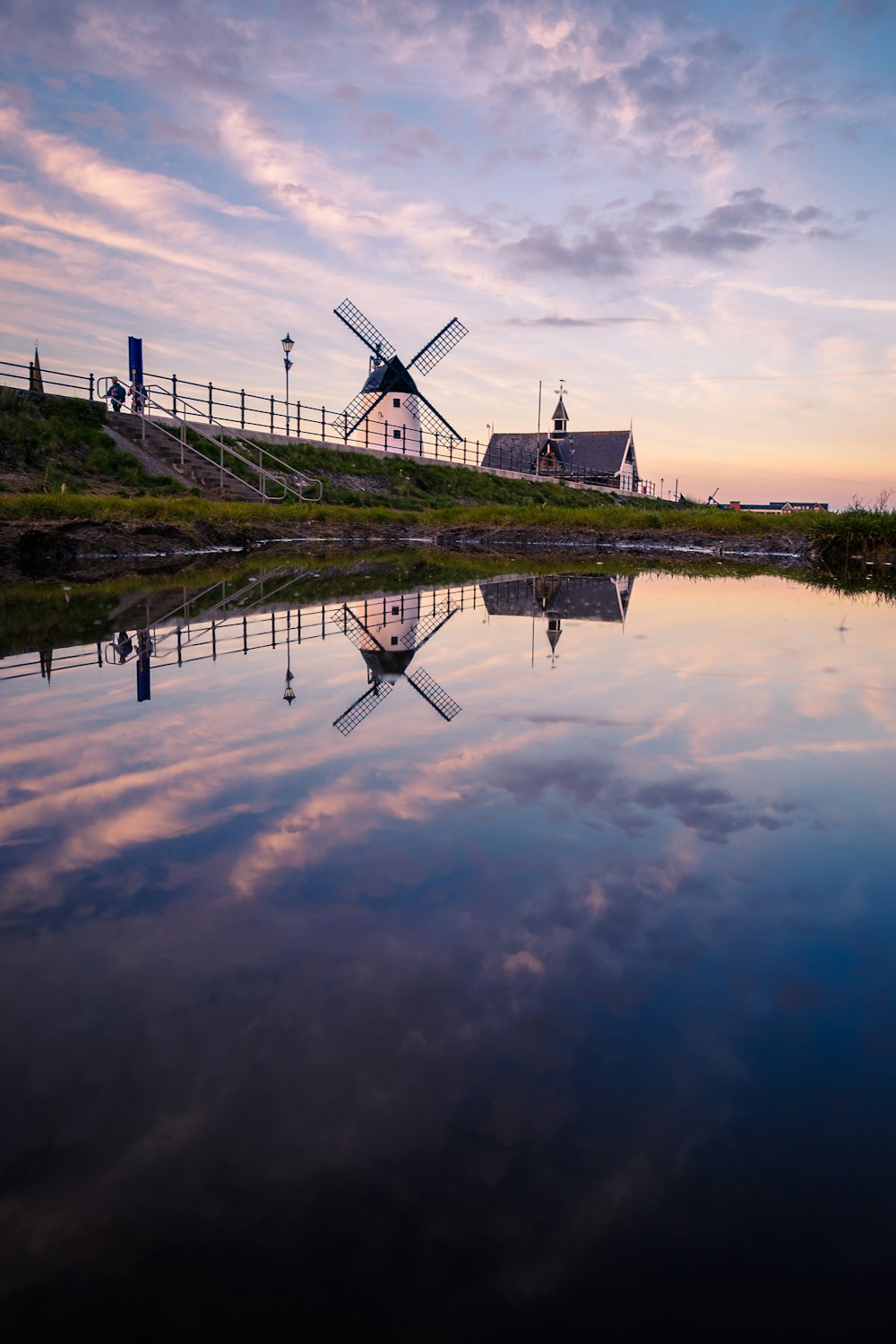 a windmill sitting on top of a hill next to a body of water