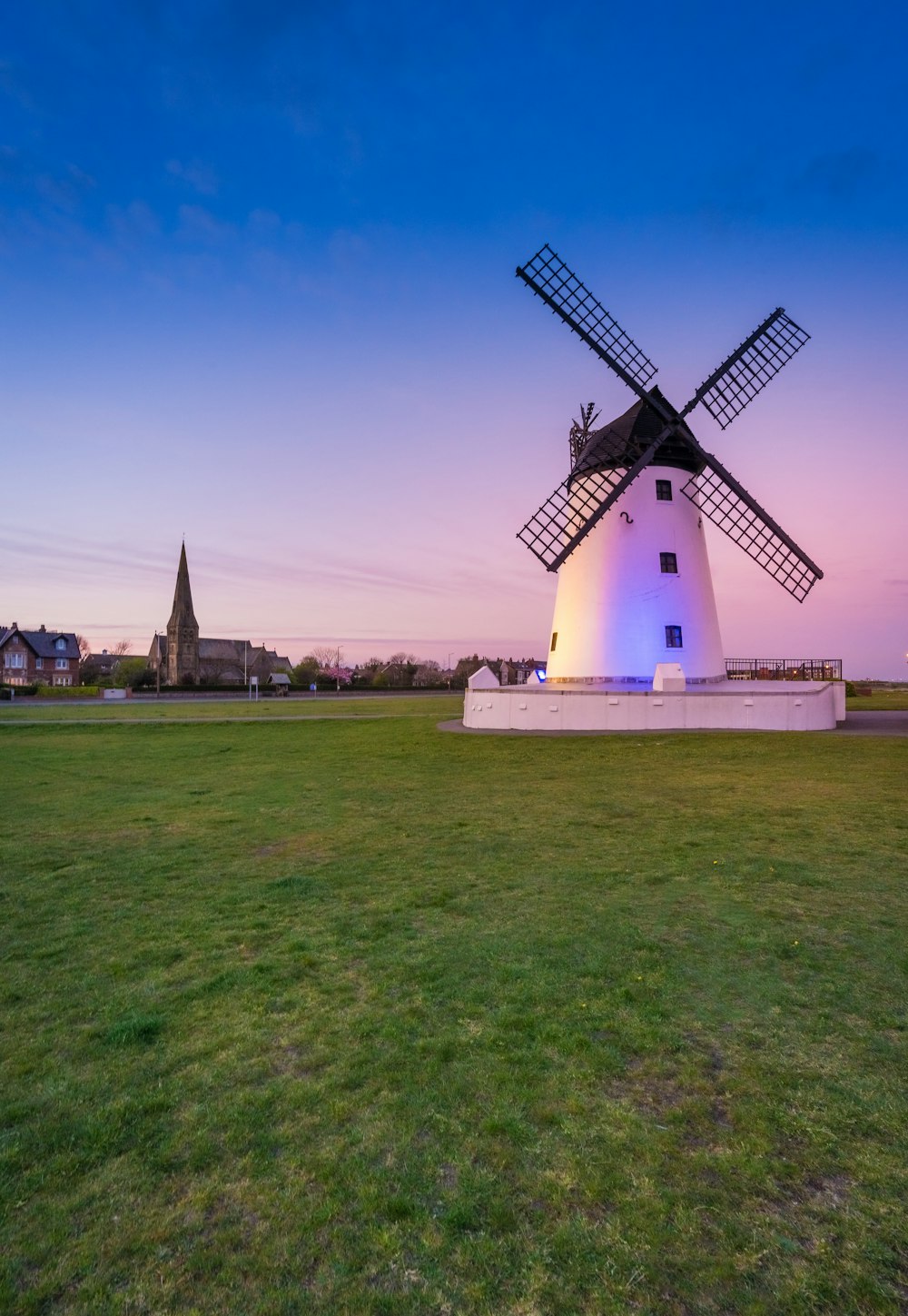 a windmill in the middle of a grassy field