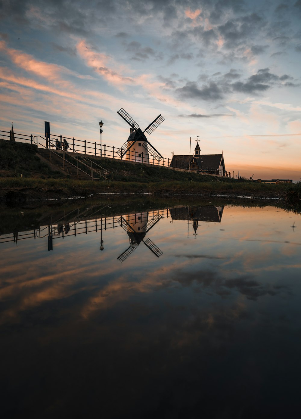 Eine Windmühle, die auf einem Hügel neben einem Gewässer sitzt