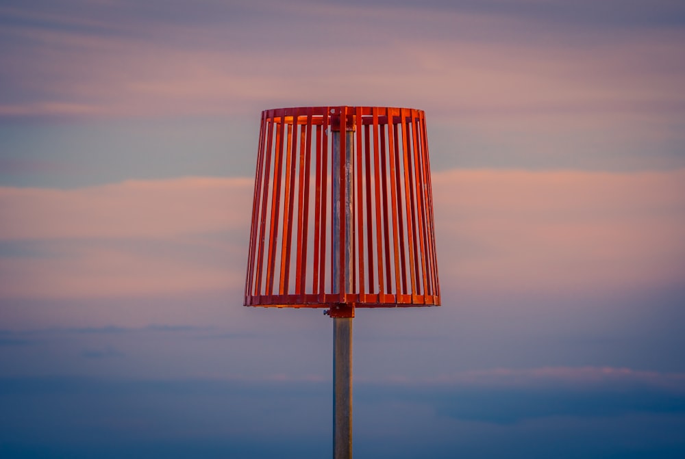 a red lamp on a pole with a sky in the background