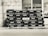 A stack of empty glass bottles organized neatly in black crates bearing the Pepsi logo and Arabic script. The crates are arranged in several rows and columns against a tiled building facade.