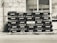 A stack of empty glass bottles organized neatly in black crates bearing the Pepsi logo and Arabic script. The crates are arranged in several rows and columns against a tiled building facade.