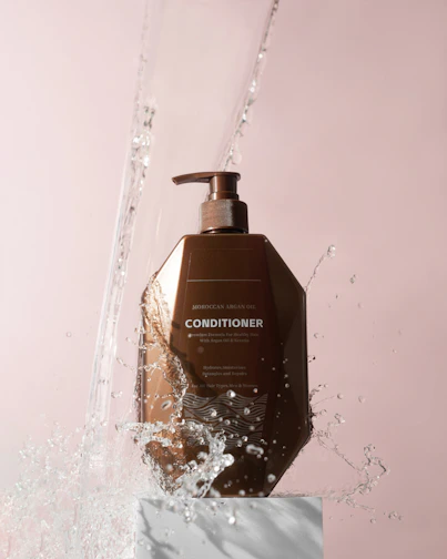 Close-up of a luxurious conditioner bottle with creamy texture dripping from the nozzle.