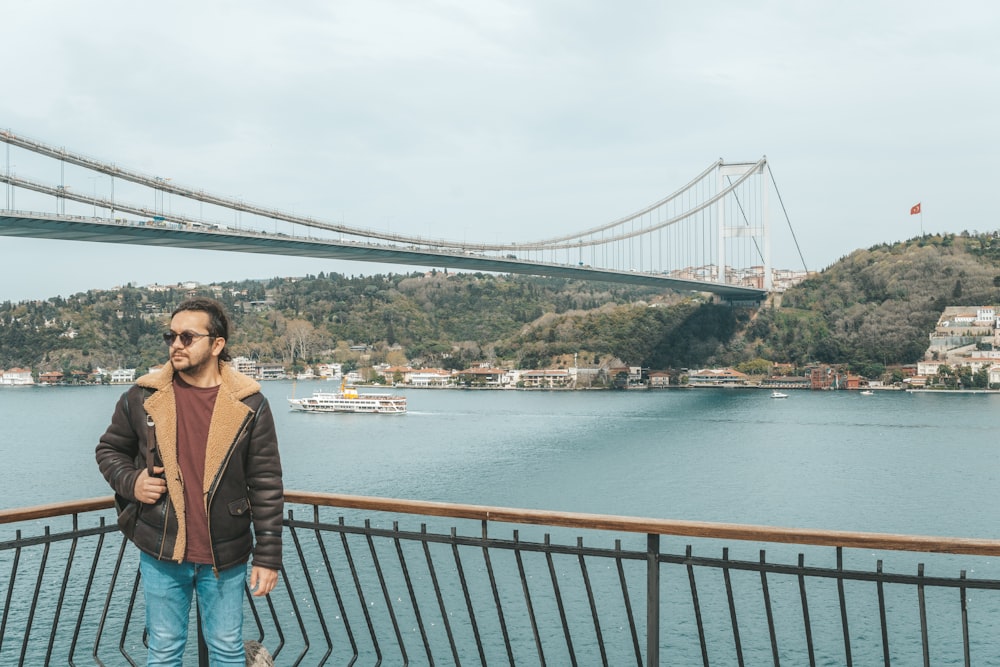 a man standing next to a fence near a body of water