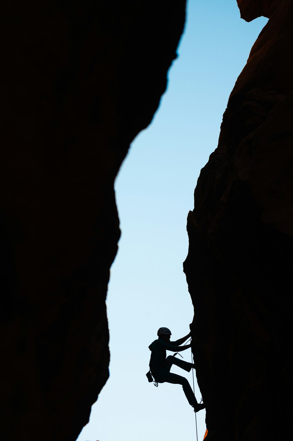 Un homme grimpant sur le flanc d’une montagne