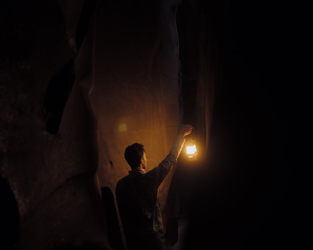 um homem segurando uma lanterna no escuro