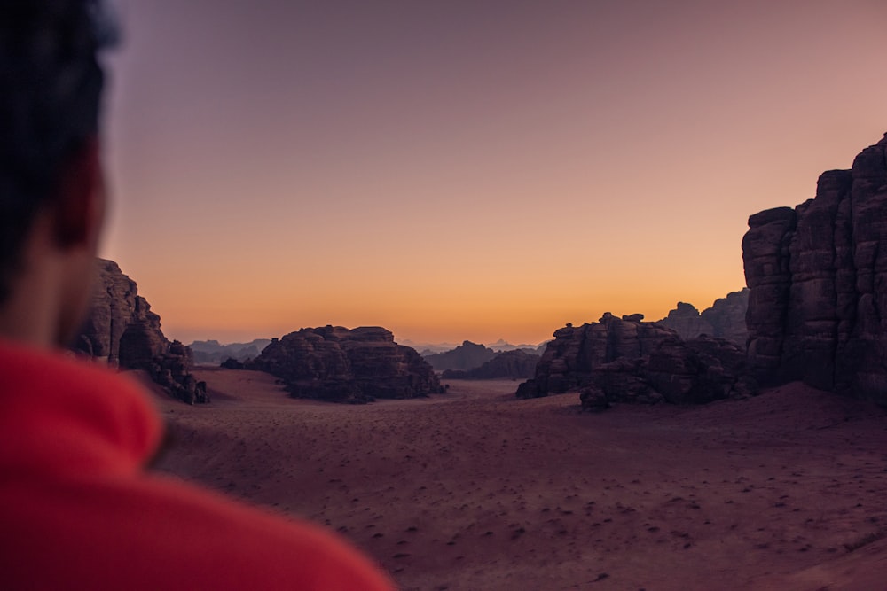a man in a red shirt is looking at the desert