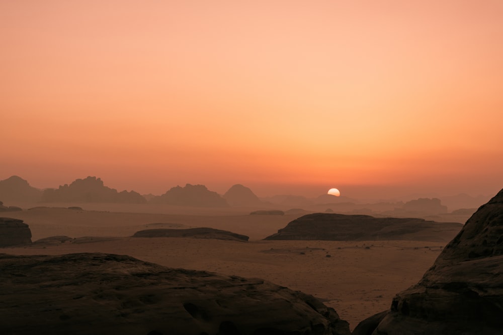 the sun is setting over a desert landscape