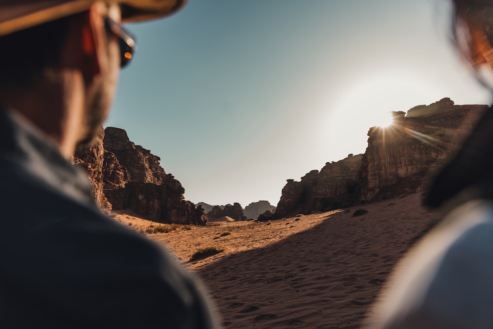 um homem parado no deserto olhando para o sol