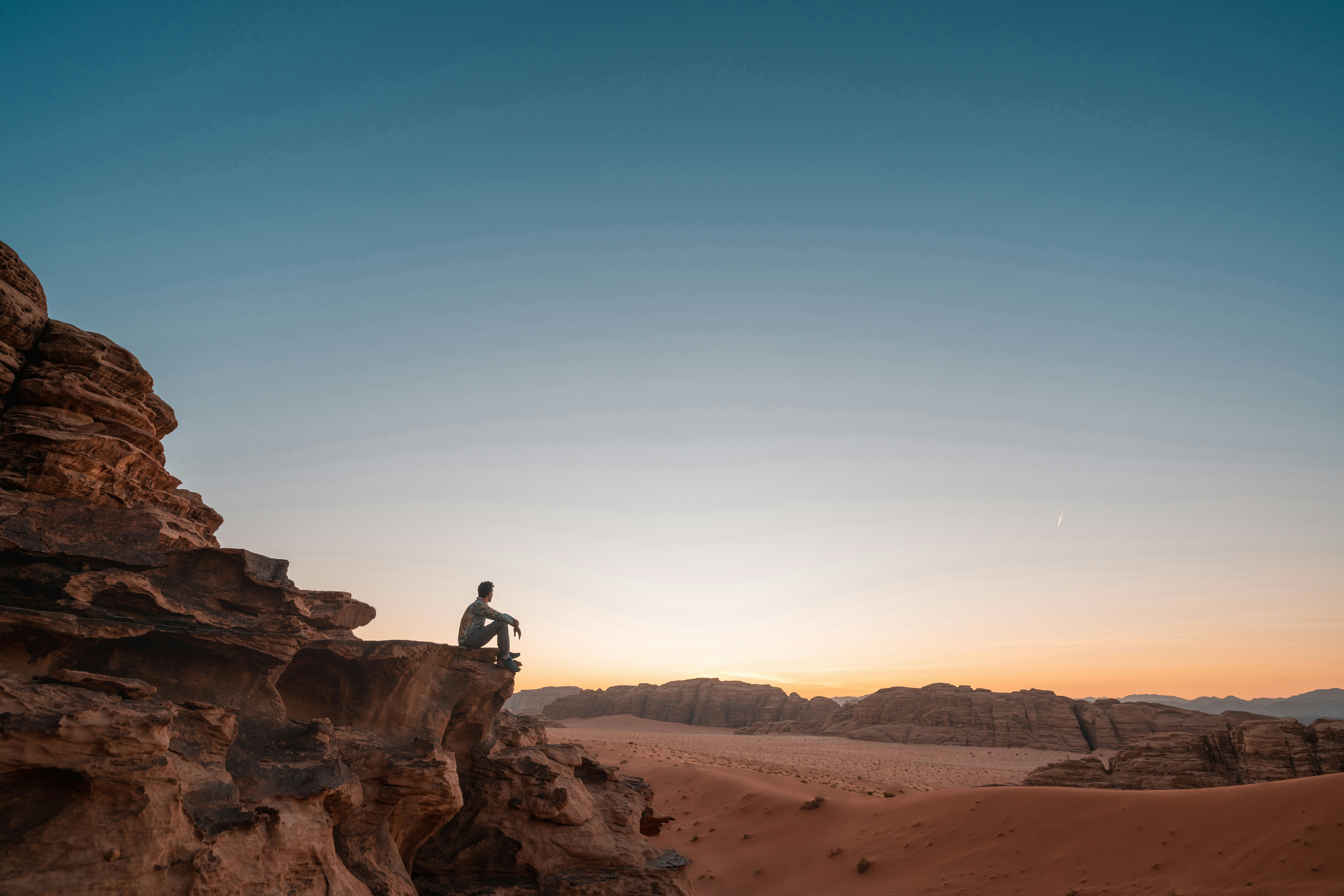 a man sitting on a rock in the desert