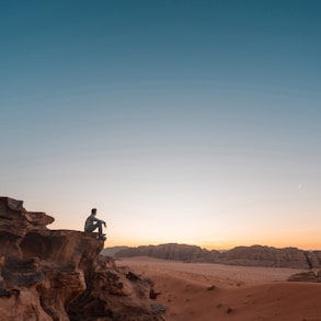 a man sitting on a rock in the desert