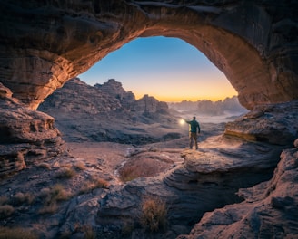a man standing in a cave at sunset