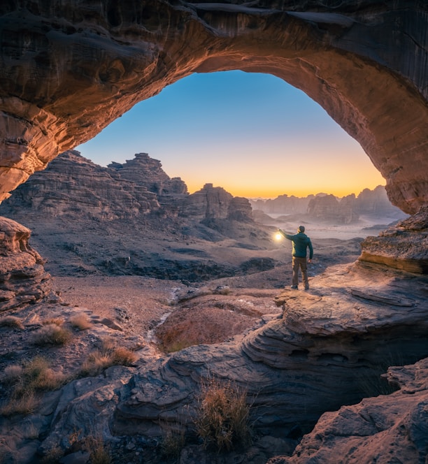 a man standing in a cave at sunset