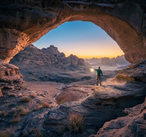 a man standing in a cave at sunset