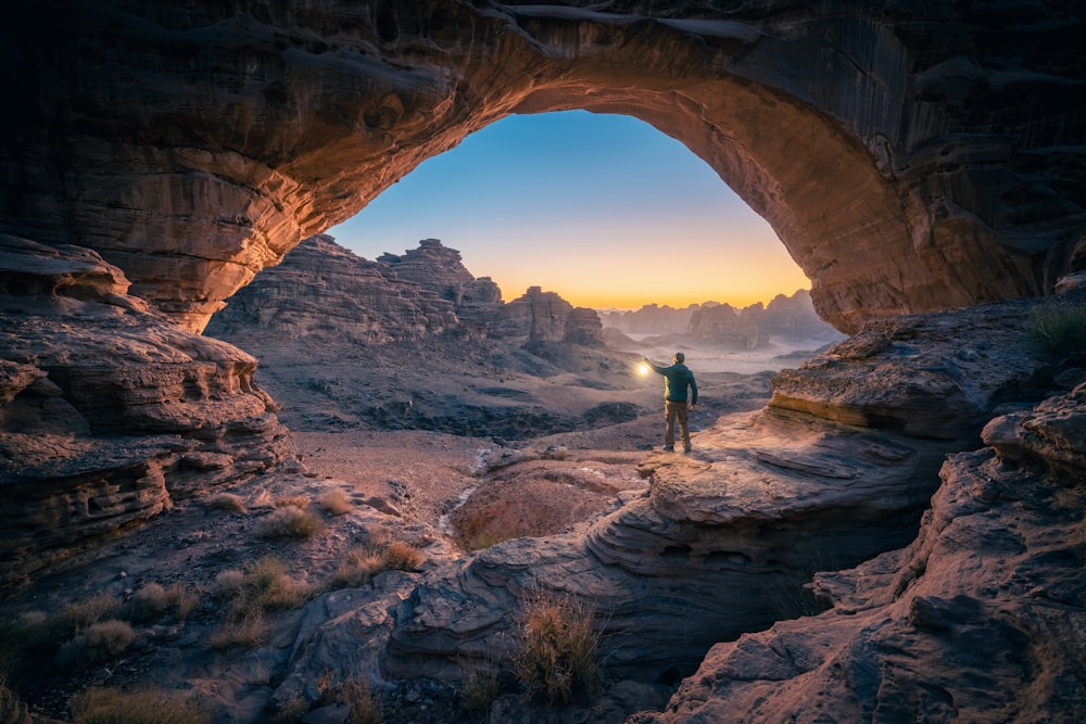 um homem em pé em uma caverna ao pôr do sol
