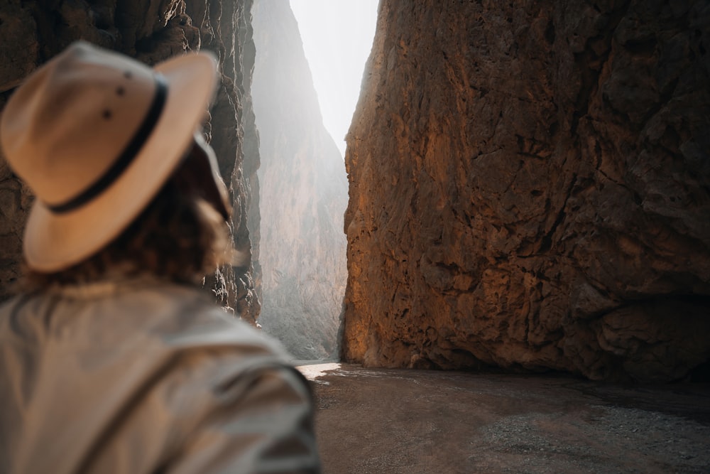 a person wearing a hat standing in front of a mountain