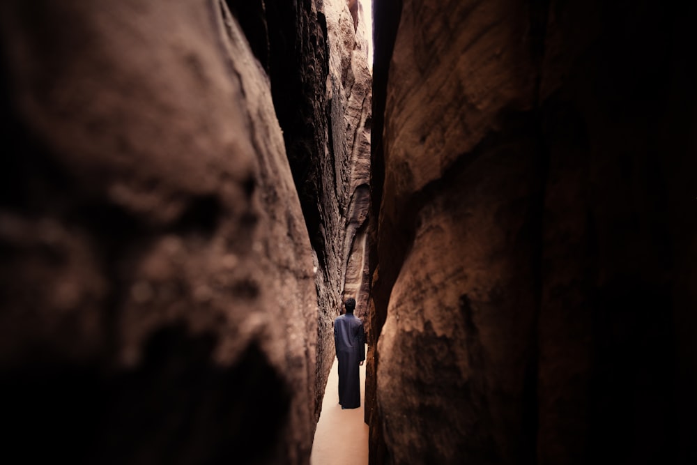 a man is walking through a narrow canyon
