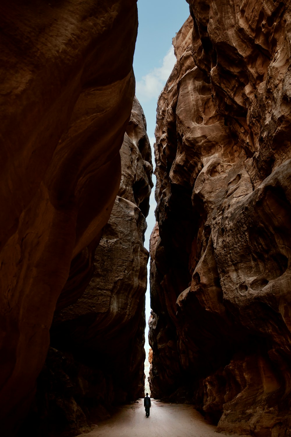 a person walking through a narrow slot in a canyon