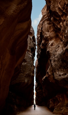 a person walking through a narrow slot in a canyon