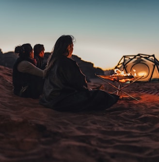 a group of people sitting on top of a sandy beach