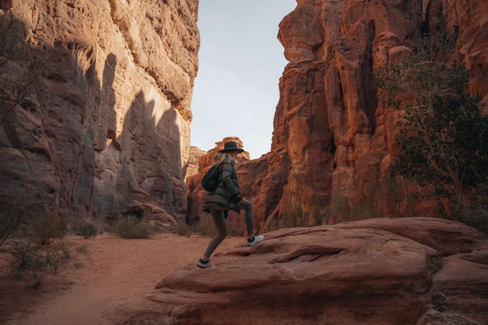 a man in a hat is walking through a canyon