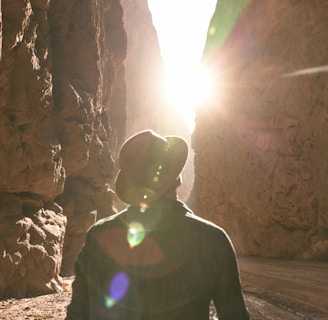 a man standing in a canyon with the sun shining through the rocks