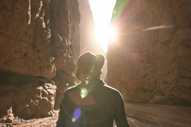 a man standing in a canyon with the sun shining through the rocks