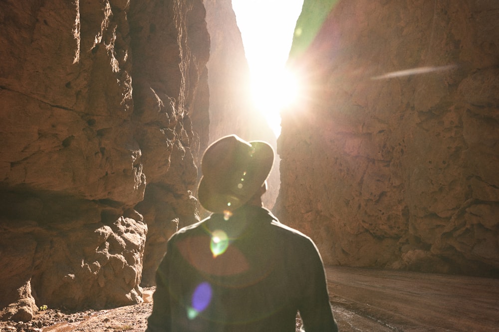 岩の間から太陽が輝く峡谷に立つ男