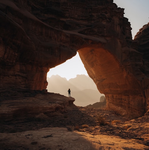 a person standing at the entrance to a cave