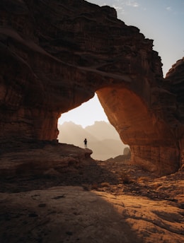 a person standing at the entrance to a cave