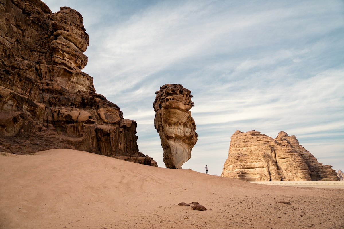 Uma paisagem desértica de areias vermelhas e formações rochosas de arenito espetaculares sob um céu amplo — o deserto de Hisma em NEOM, Arábia Saudita — simbolizando o contraste entre a esterilidade do deserto e a promessa divina de rios e jardins