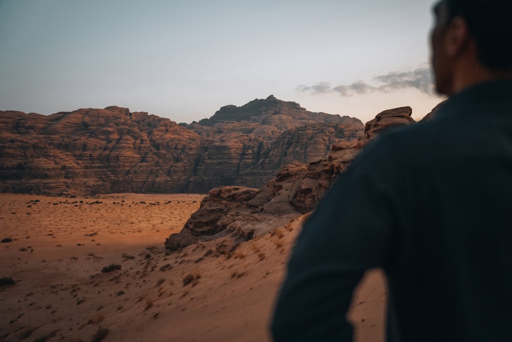 a man standing on top of a sandy hill