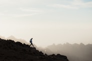 a man running up a mountain with a sky background