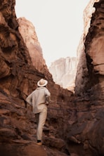 a man in a hat walking through a canyon