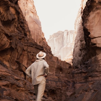 a man in a hat walking through a canyon
