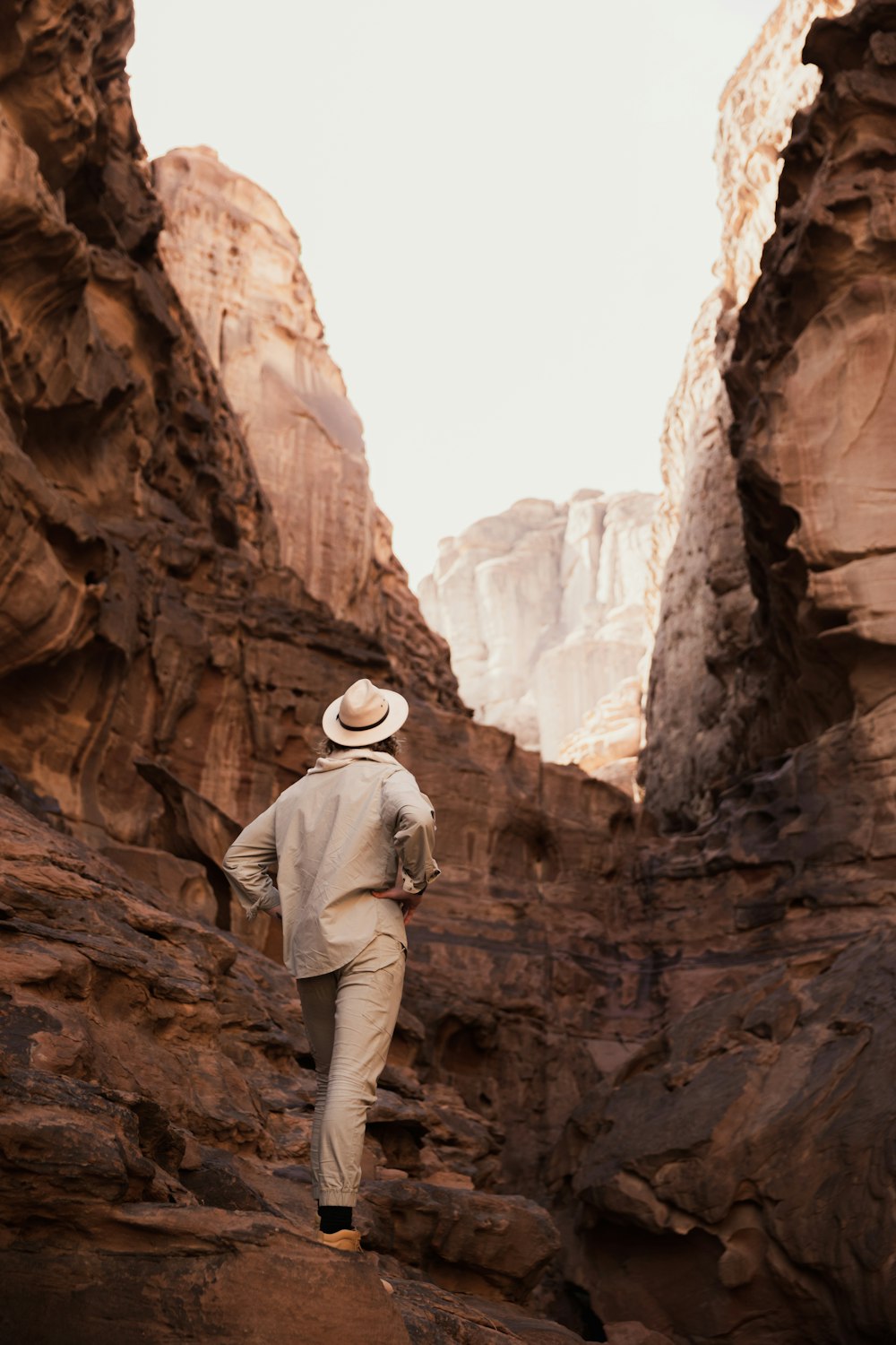 a man in a hat walking through a canyon