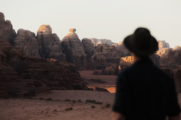 Person wearing a wide-rimmed hat looking out at a rocky landscape