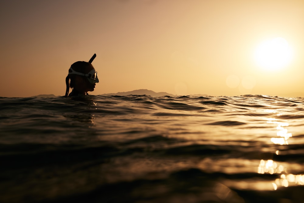eine Person, die bei Sonnenuntergang im Meer schwimmt