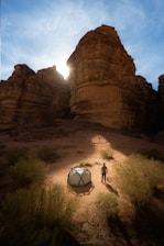 a man standing next to a tent in the desert